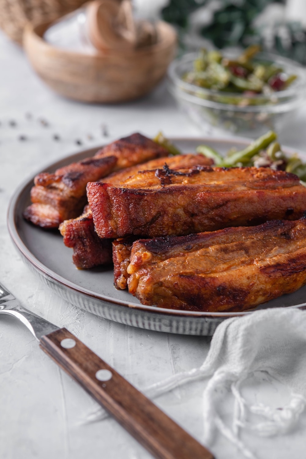 A closer look at roasted pork belly on a plate with green bean salad.