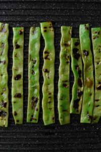 Trimmed green beans grilling on an electric grill.