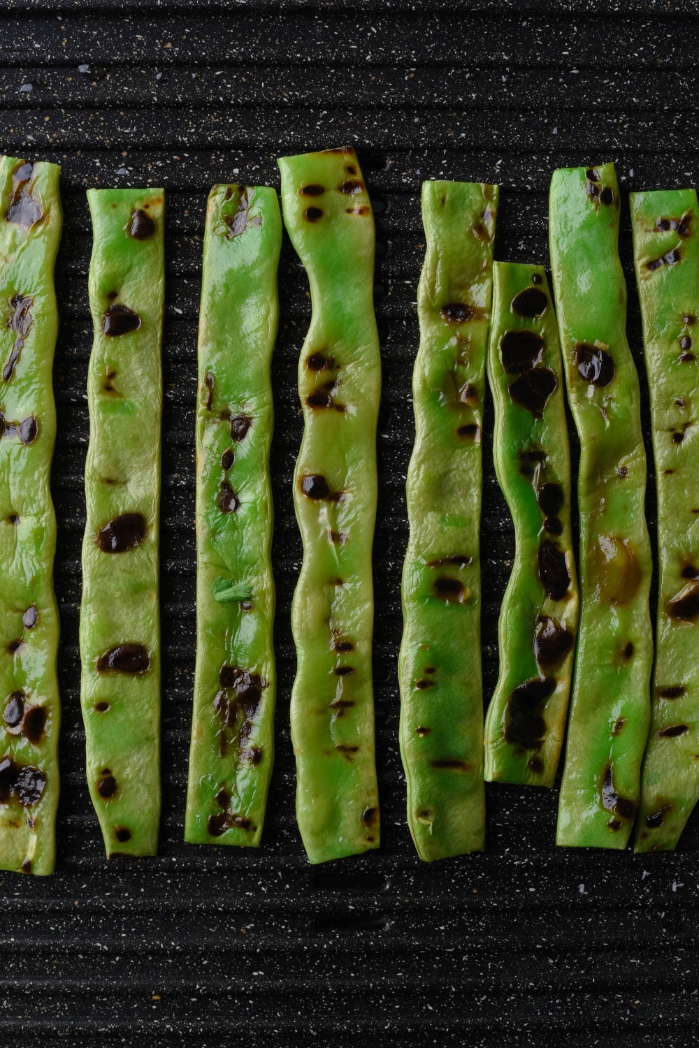 Trimmed green beans grilling on an electric grill.