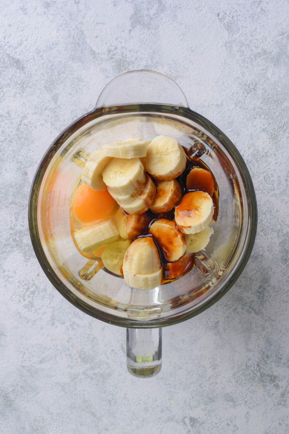 Banana slices covered in egg and date syrup in a blender.