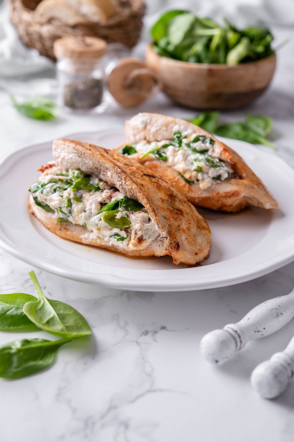 Two chicken breasts stuffed with cream cheese and spinach on a plate.