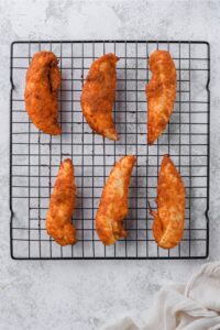 Baked chicken tenders on a baking rack.