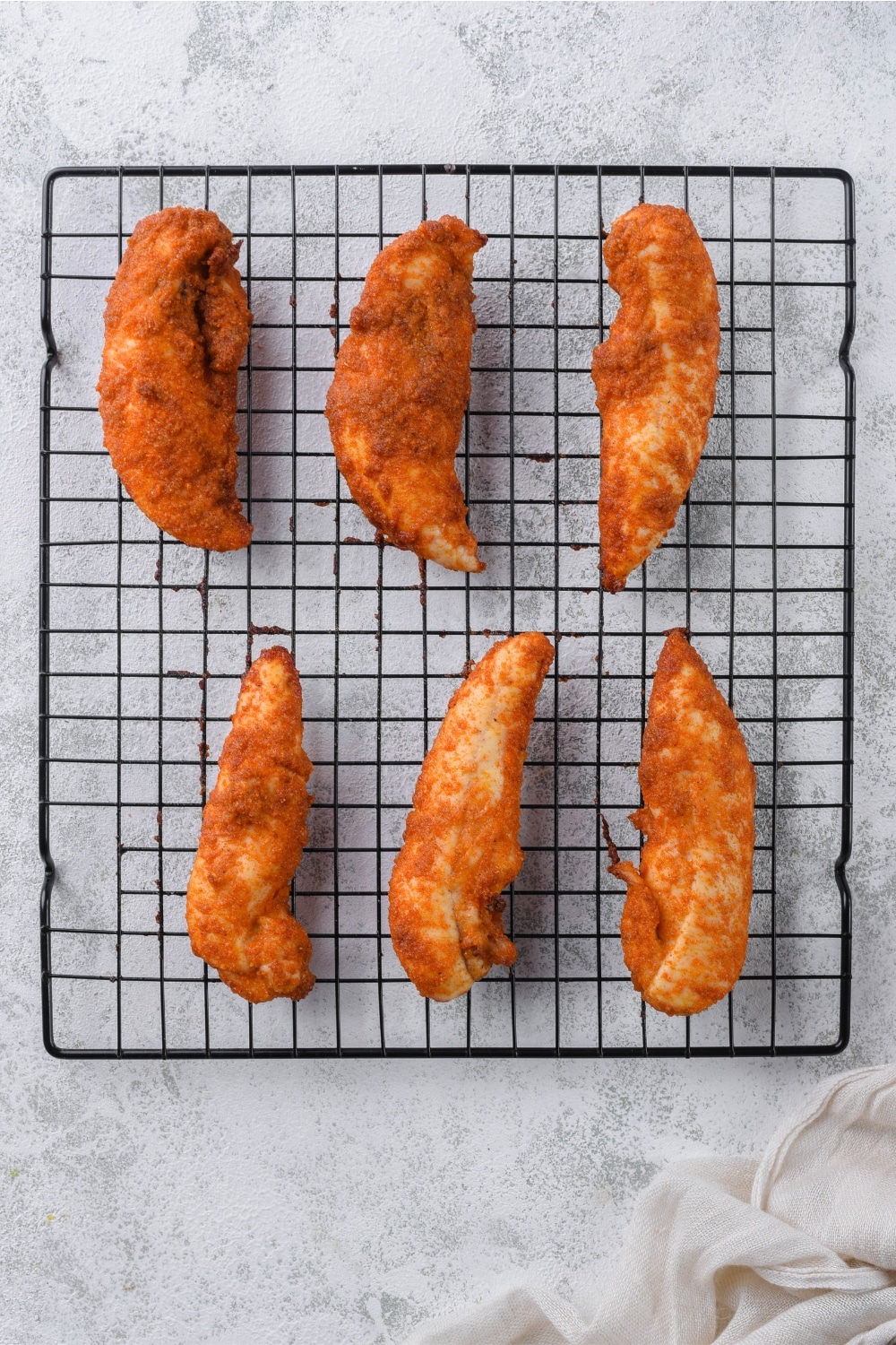 Baked chicken tenders on a baking rack.