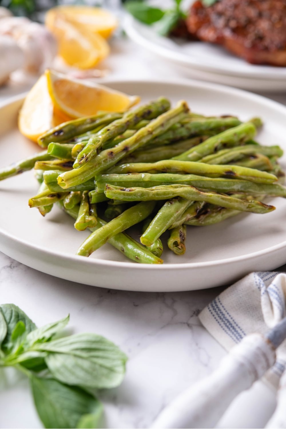 A bunch of grilled green beans on a white plate.