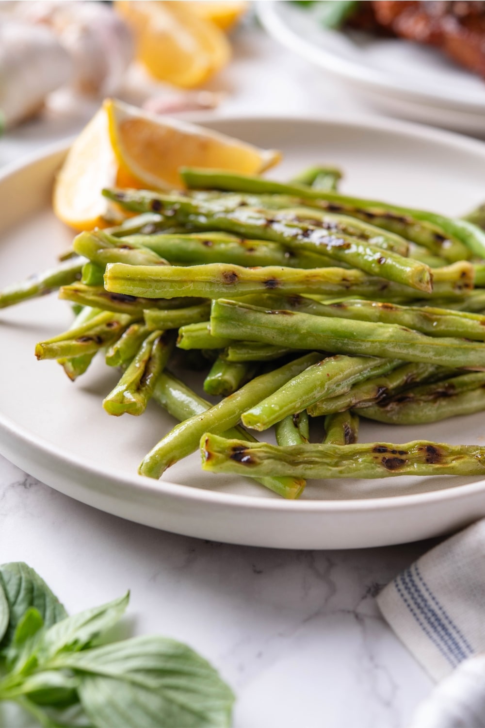 Grilled green beans on a white plate.