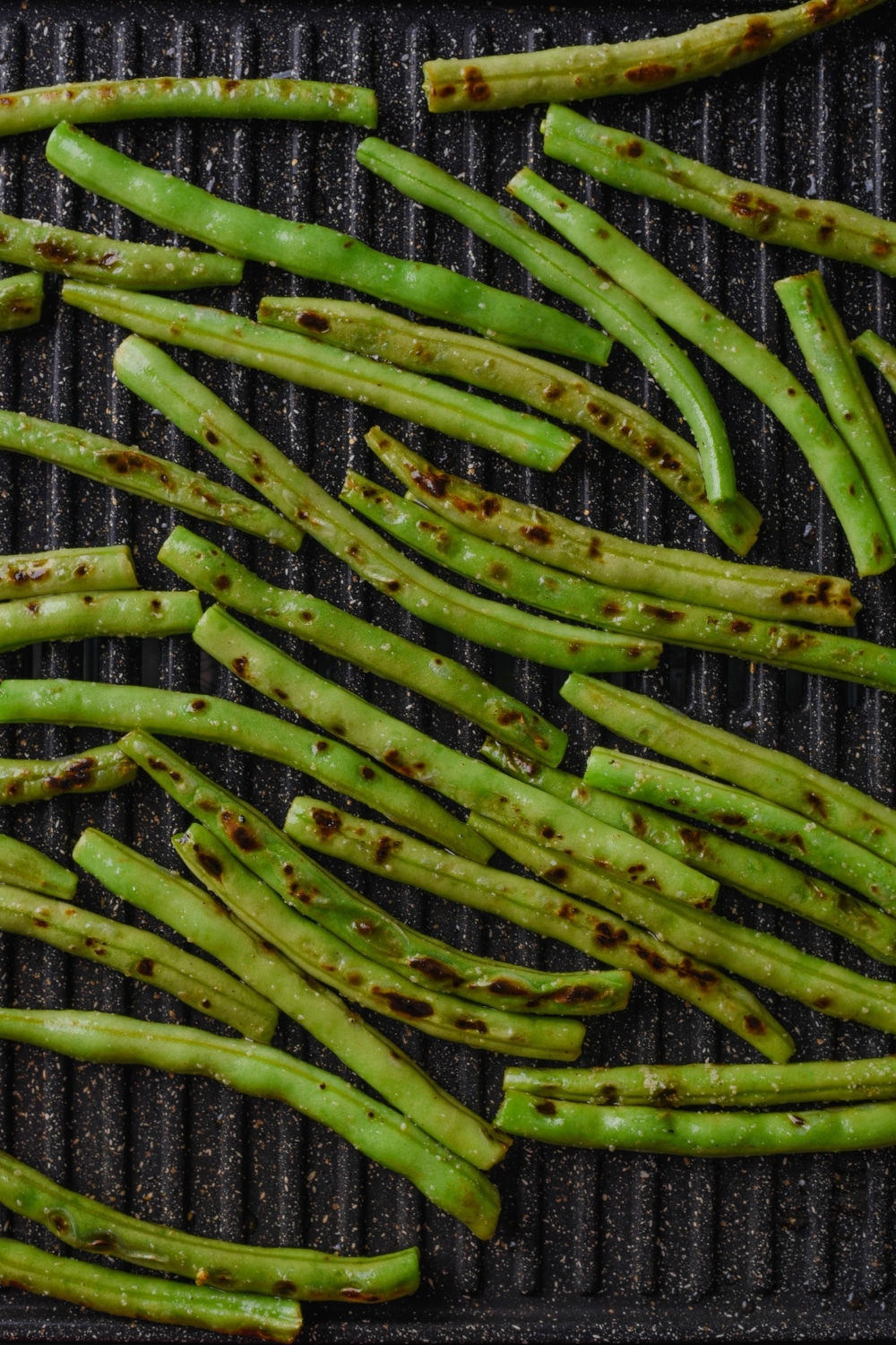 A bunch of green beans grilling on a grill.