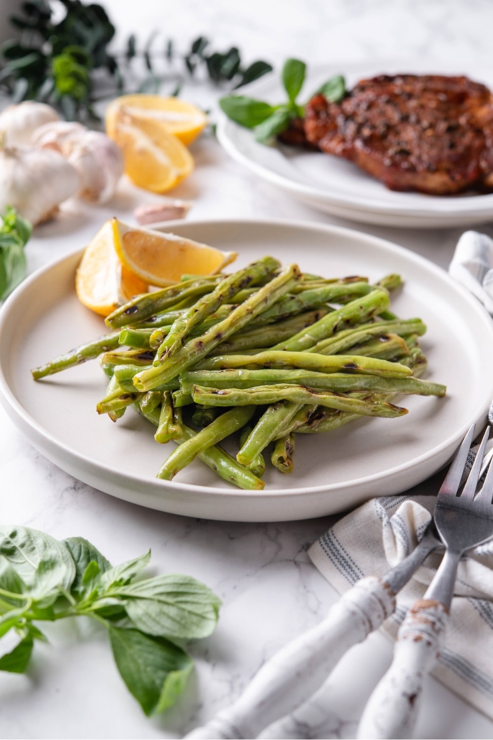 A white plate that has a bunch of grilled green beans on it.