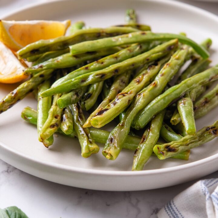 Grilled greens stacked on top of one another on a white plate.