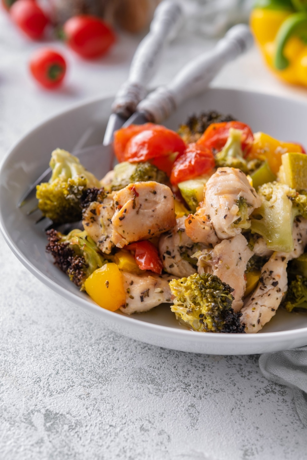 A closer look at roasted chicken and veggies on a white plate with two forks.