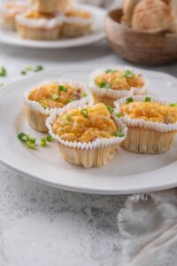 Four sausage egg muffin cups garnished with chopped green onion on a plate.