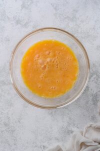 A glass bowl of beaten eggs.