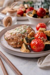 Baked Italian chicken with cherry tomatoes and zucchini on a plate.