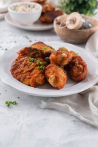 A plate of baked chicken legs and thighs garnished with parsley.