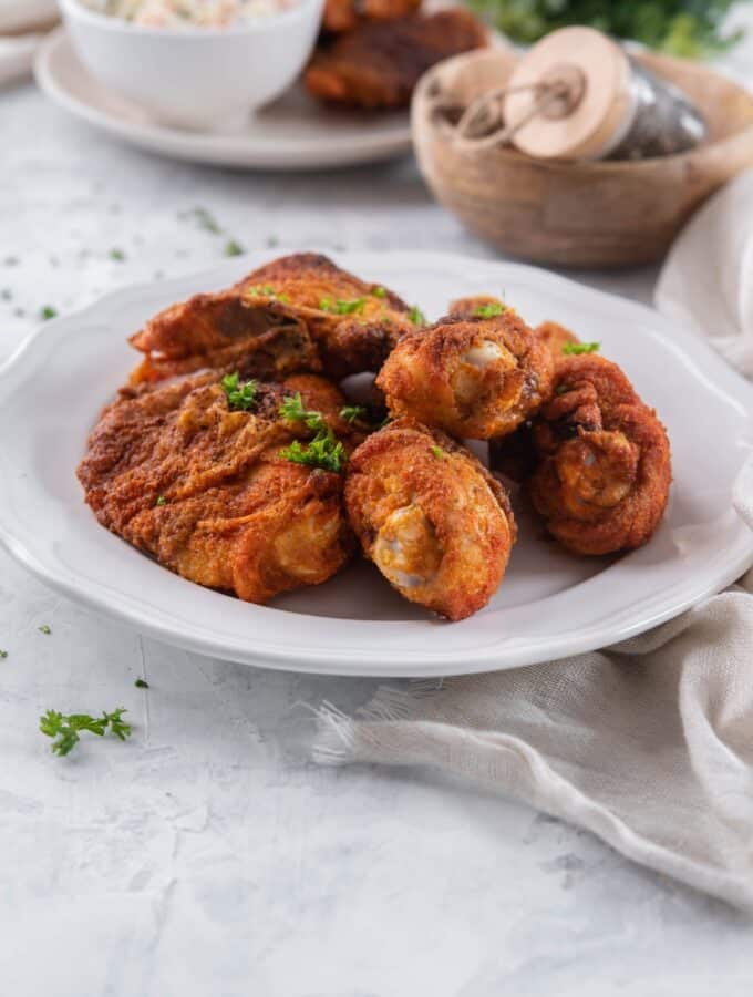 A plate of baked chicken legs and thighs garnished with parsley.