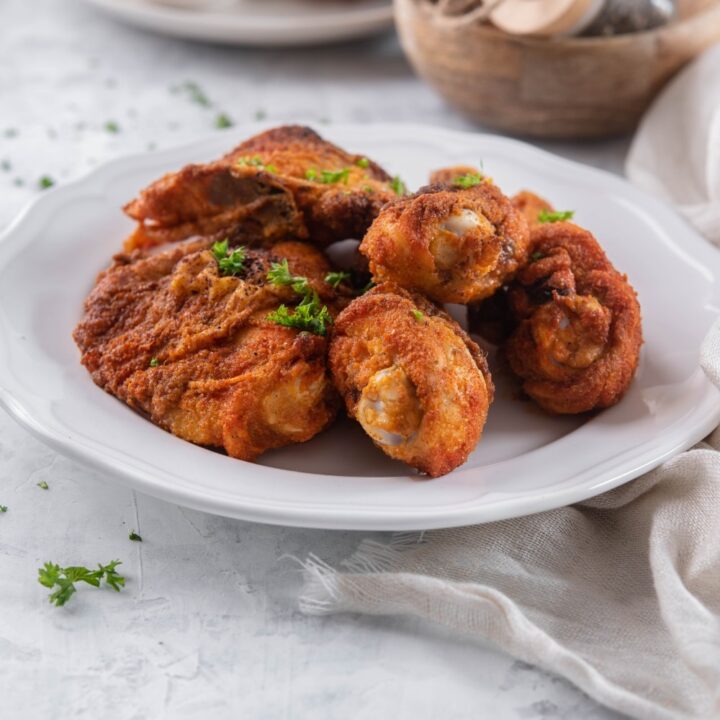 A plate of baked chicken legs and thighs garnished with parsley.