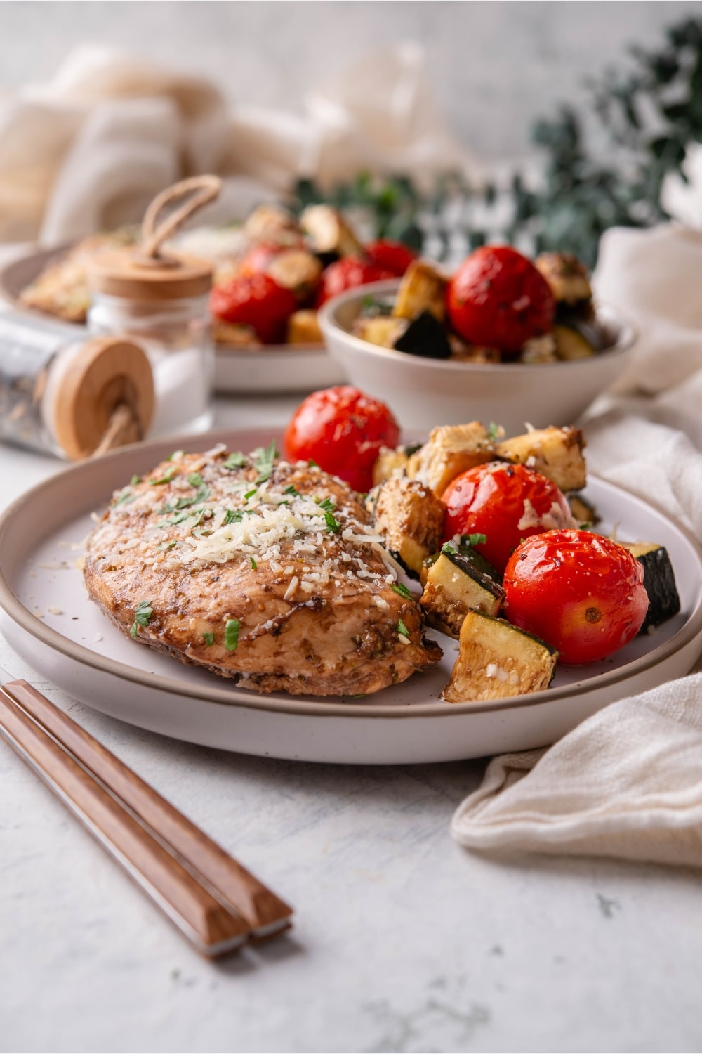 Italian baked chicken with roasted vegetables on a plate.