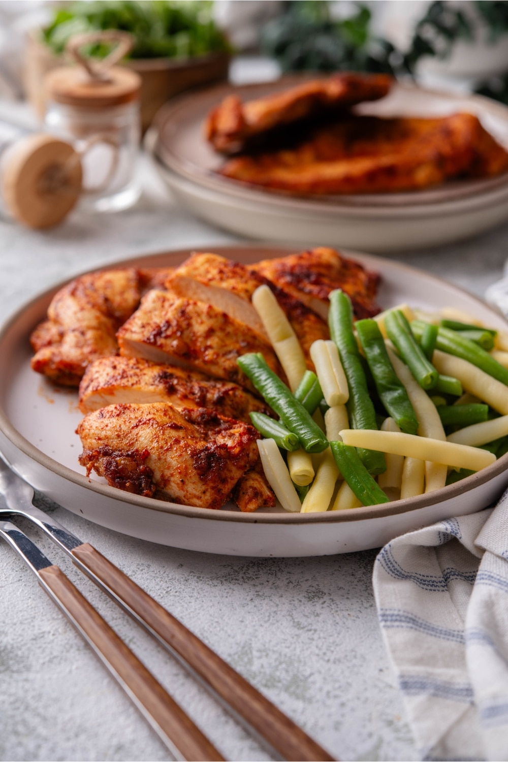 A plate of baked thin chicken breasts and steamed string beans.