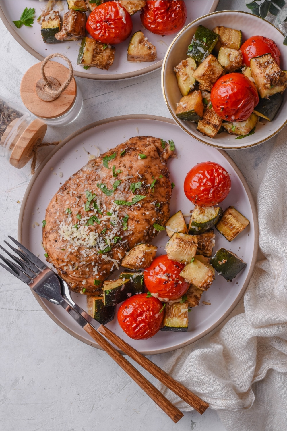 Top view of a plate of Italian baked chicken served with roasted tomatoes and zucchini and a fork.