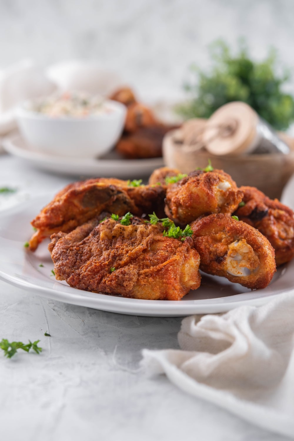 Baked chicken legs and thighs on a plate, in front of a second plate served with creamy salad.