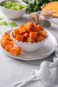 A bowl of cubed roasted butternut squash on a plate.