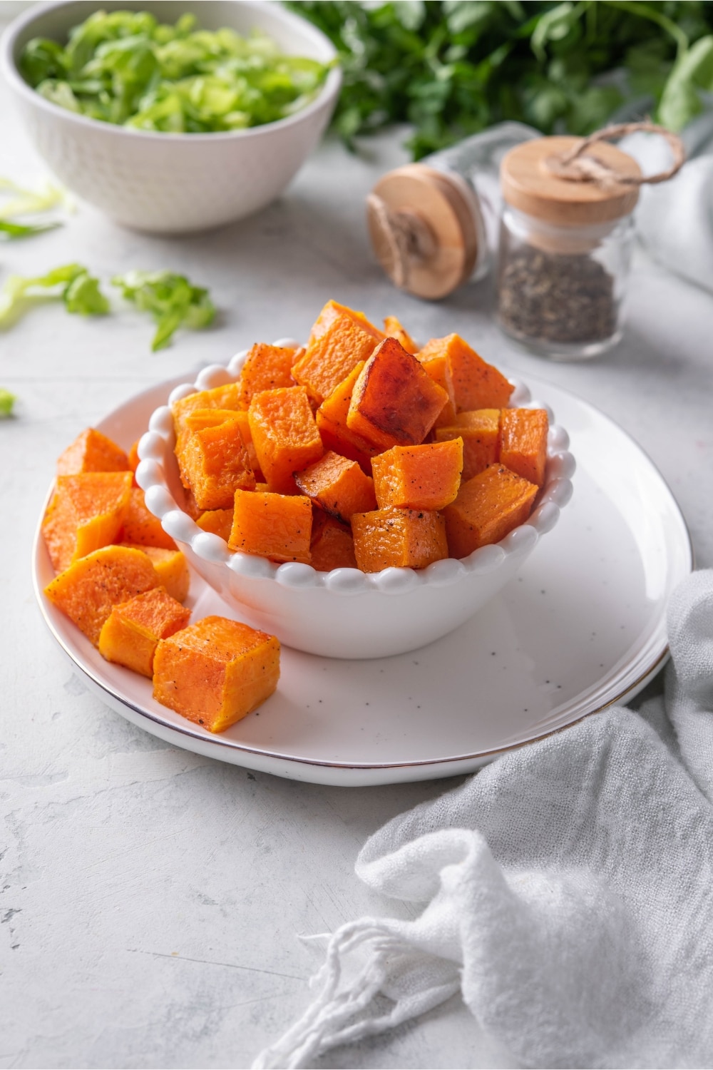 Roasted butternut squash in a white bowl on a plate.