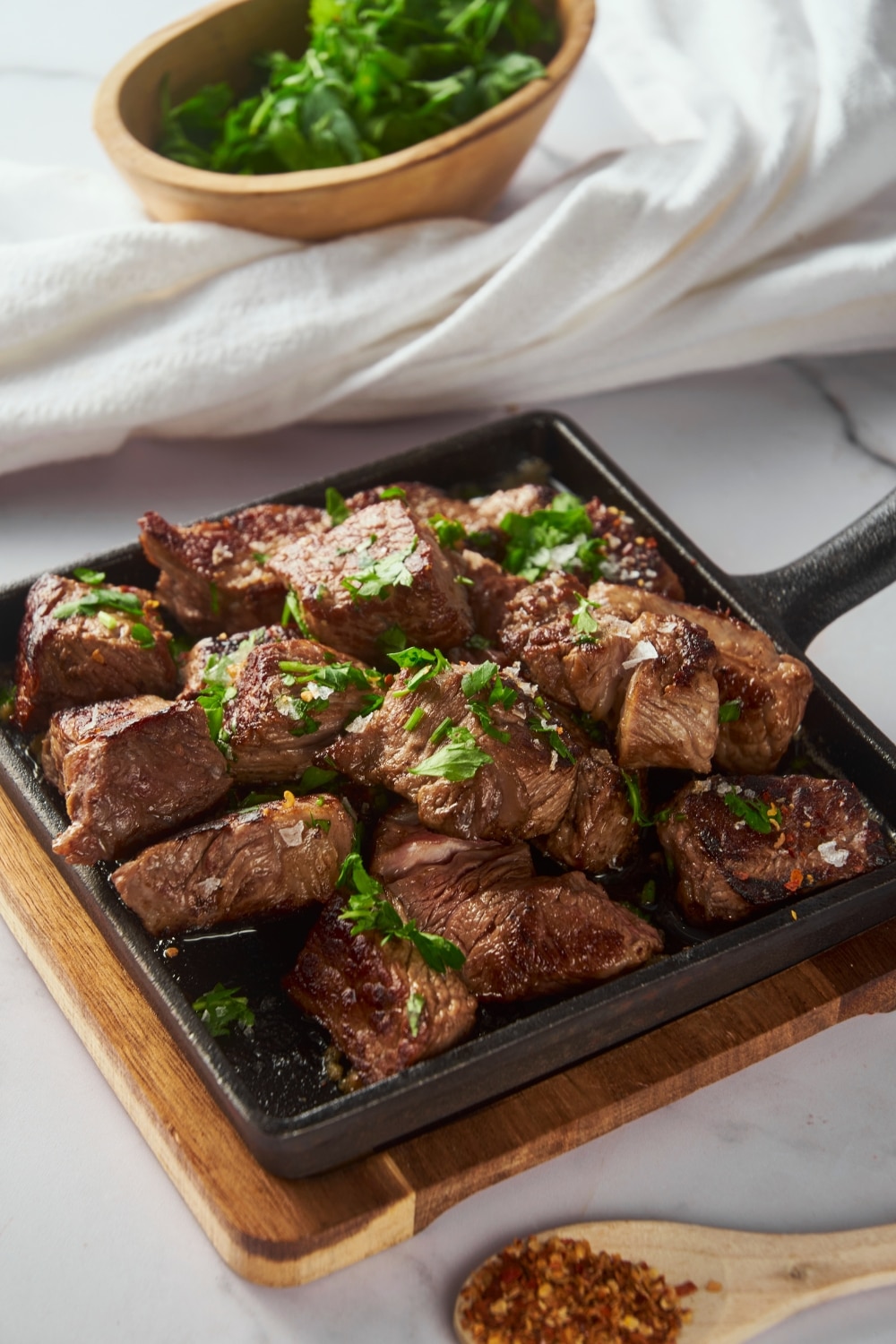 Garlic steak bites on a cast iron pan garnished with parsley.