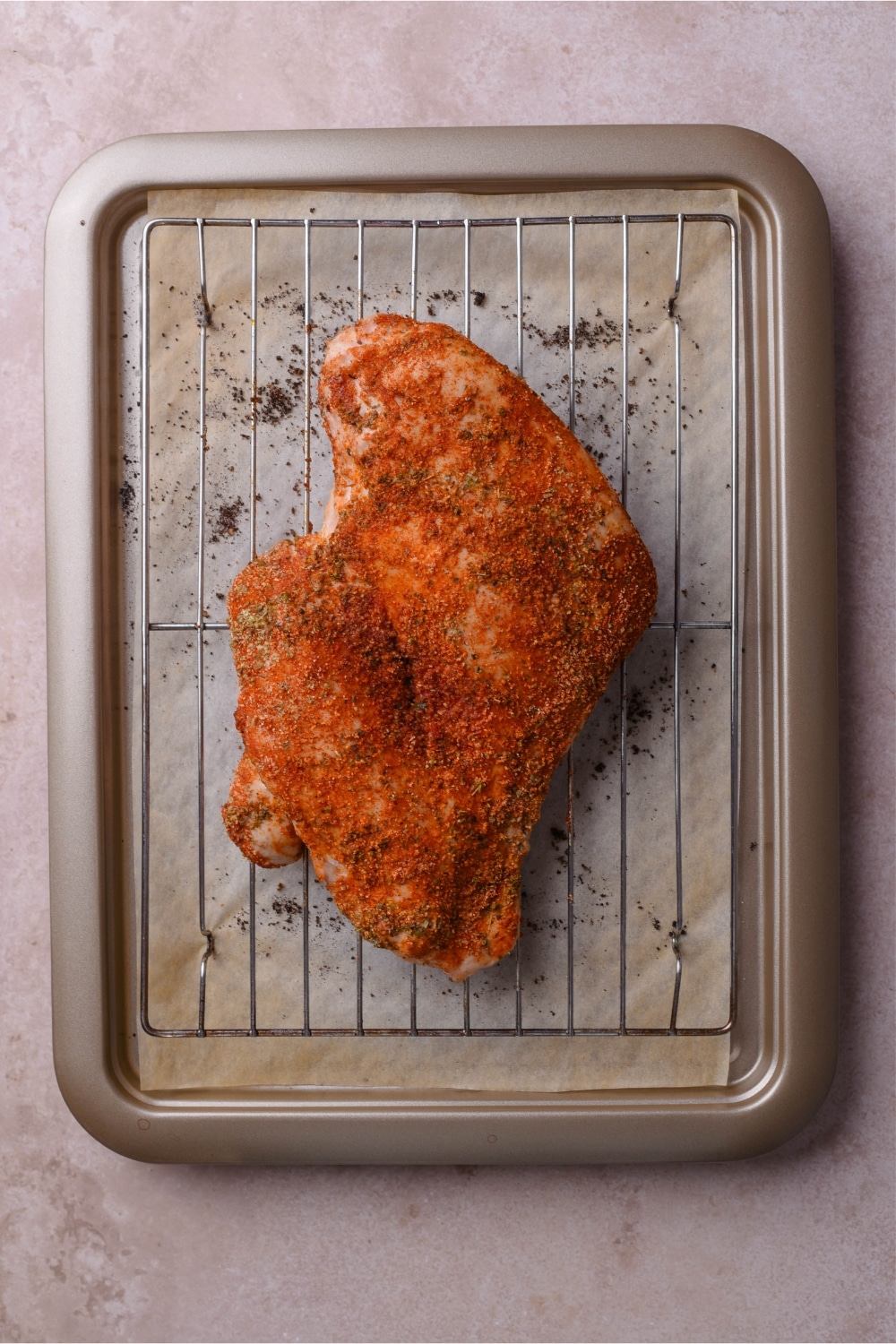 Seasoned raw boneless skinless turkey breast on a wire rack over a baking sheet.