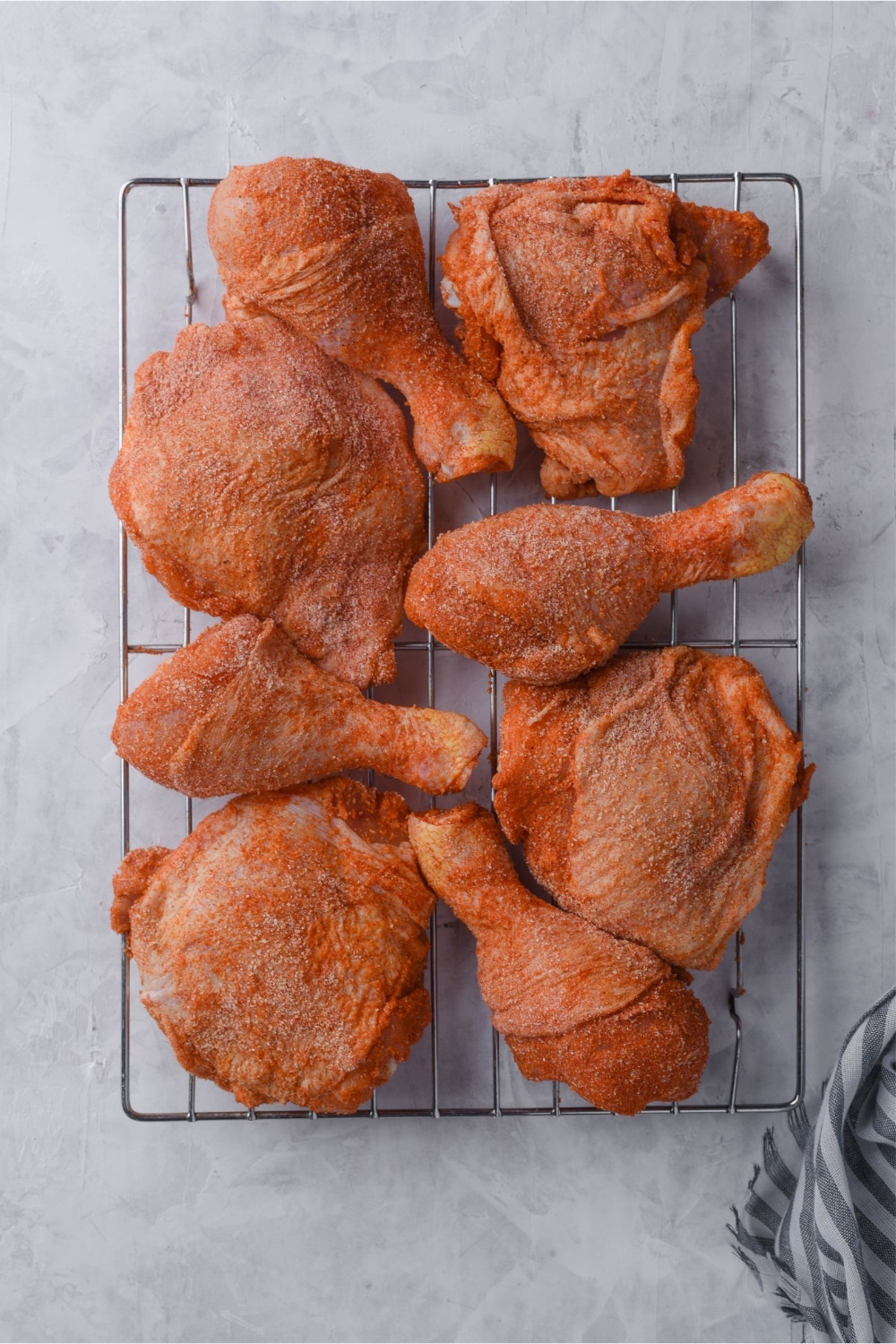 A baking tray of raw seasoned chicken legs and thighs.