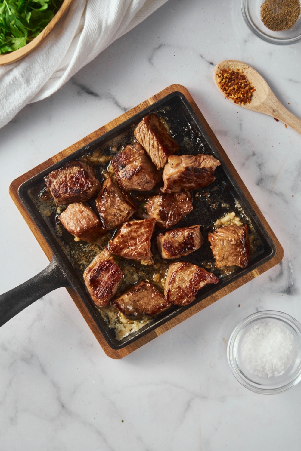 Seared steak bites with garlic and butter on a square cast iron pan.