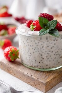 A closer look at a small glass filled with overnight oats, topped with strawberries and raspberries.