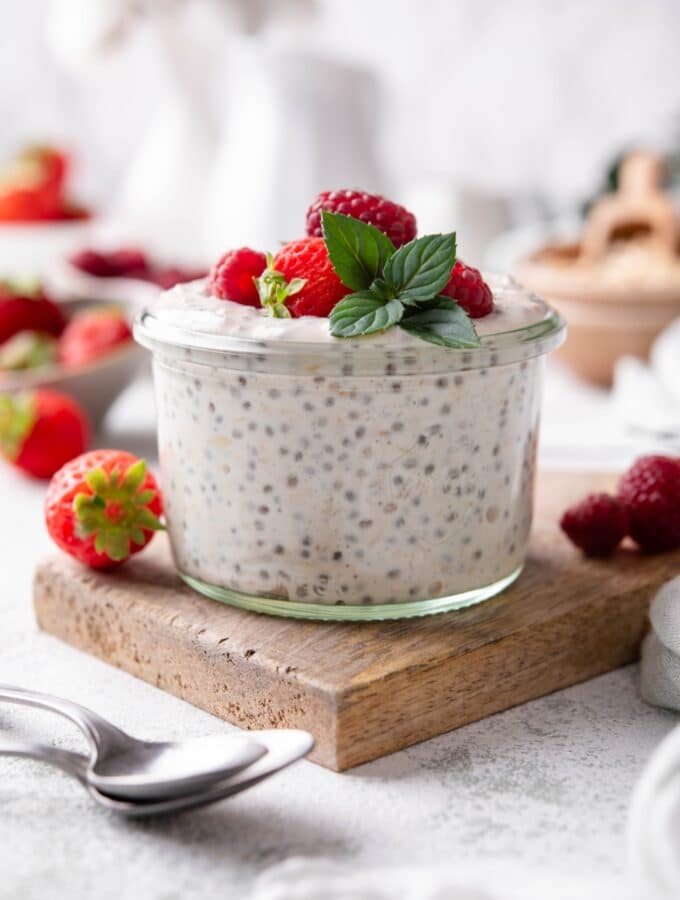 A small glass filled with overnight oats, topped with strawberries and raspberries.