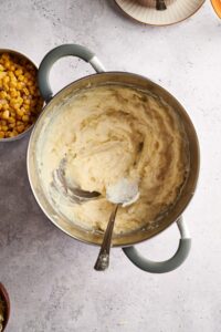 A pot filled with creamy mashed potatoes and a spoon is in the pot.