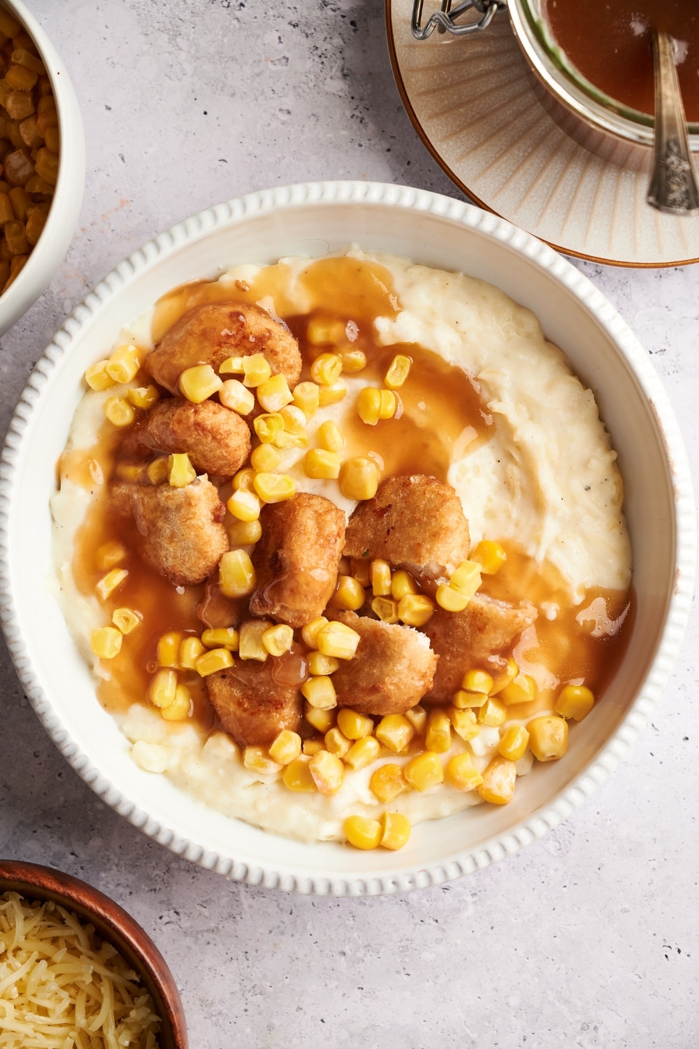 Overhead view of a KFC bowl filled with mashed potatoes, chicken nuggets, corn kernels, and brown gravy.