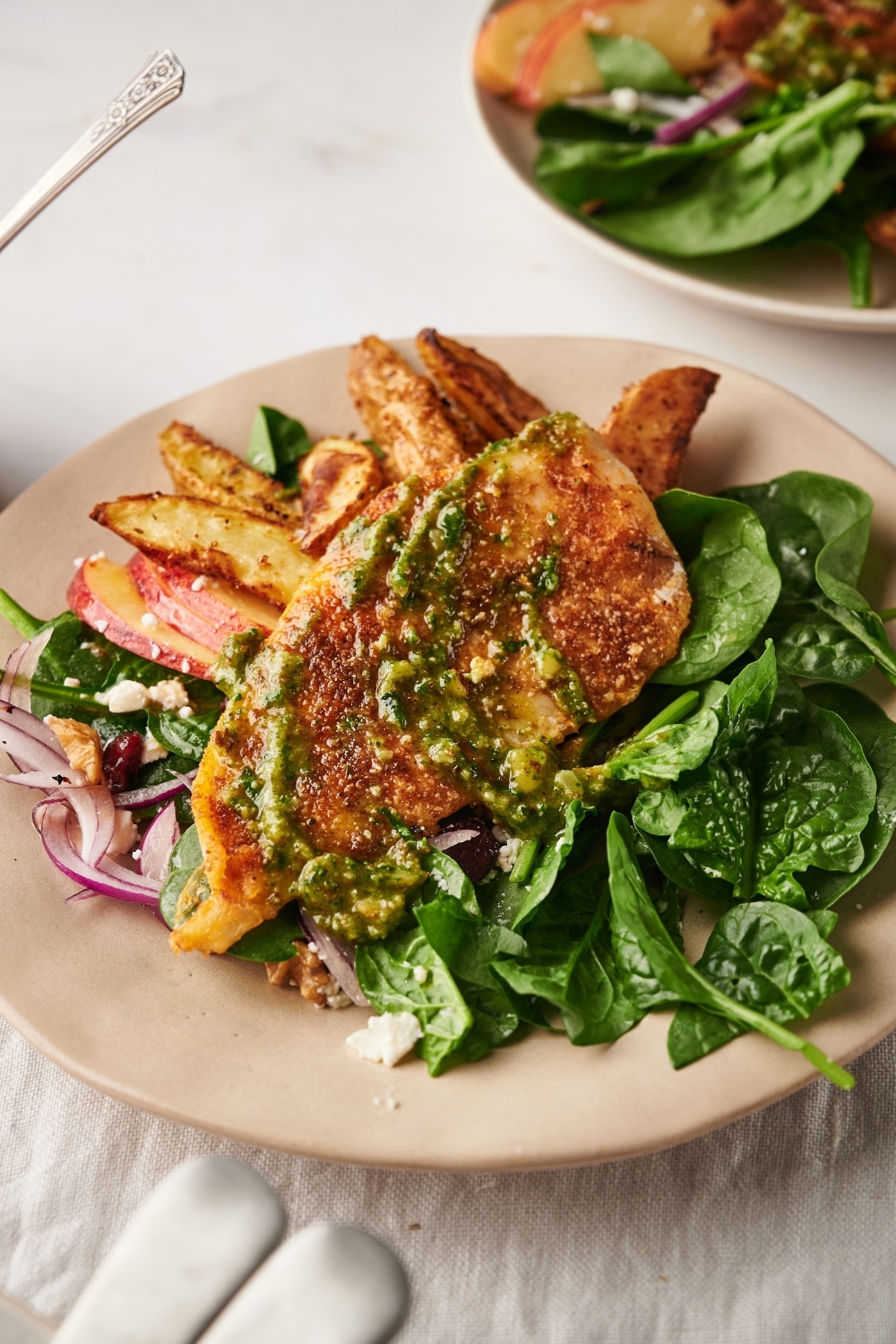 A piece of catfish with spinach and potatoes on a plate.