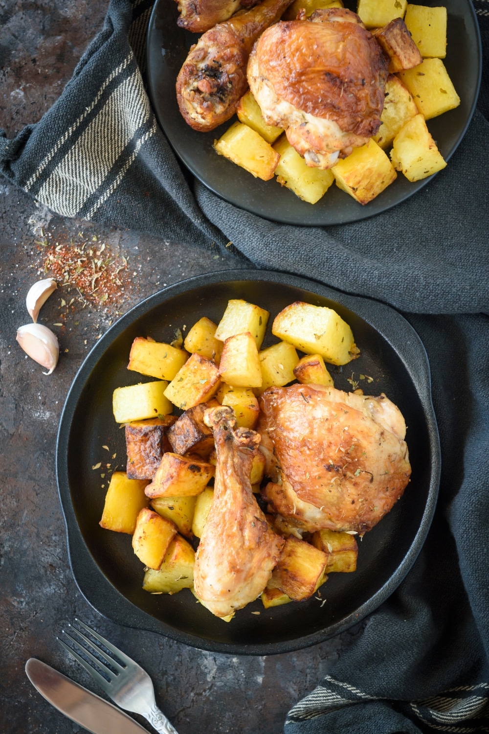 Two pieces of chicken on top of diced potatoes in a bowl.