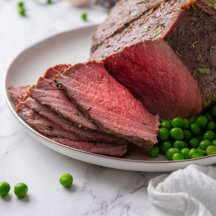 A closer look at sliced medium rare sirloin tip roast on a plate.