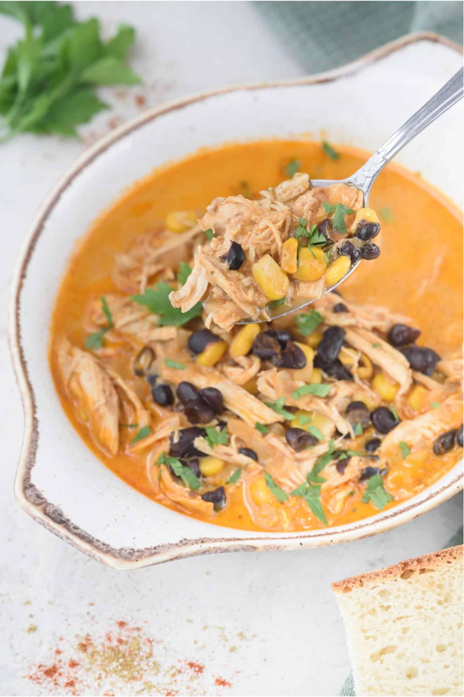 Scooping chicken enchilada soup with a spoon from a bowl.