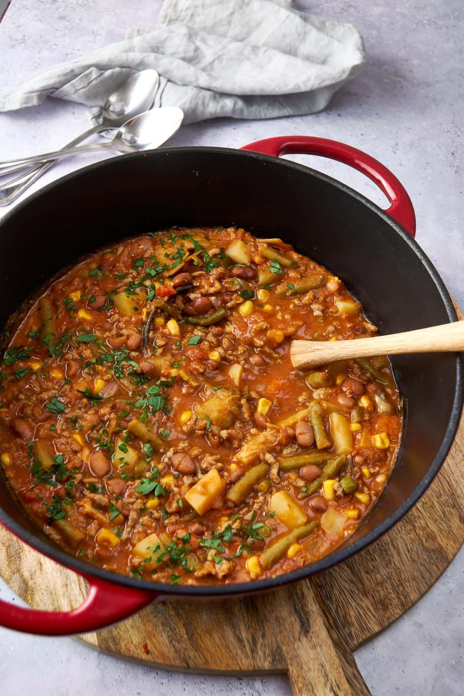 Cowboy soup in a large red pot with a wooden spoon.