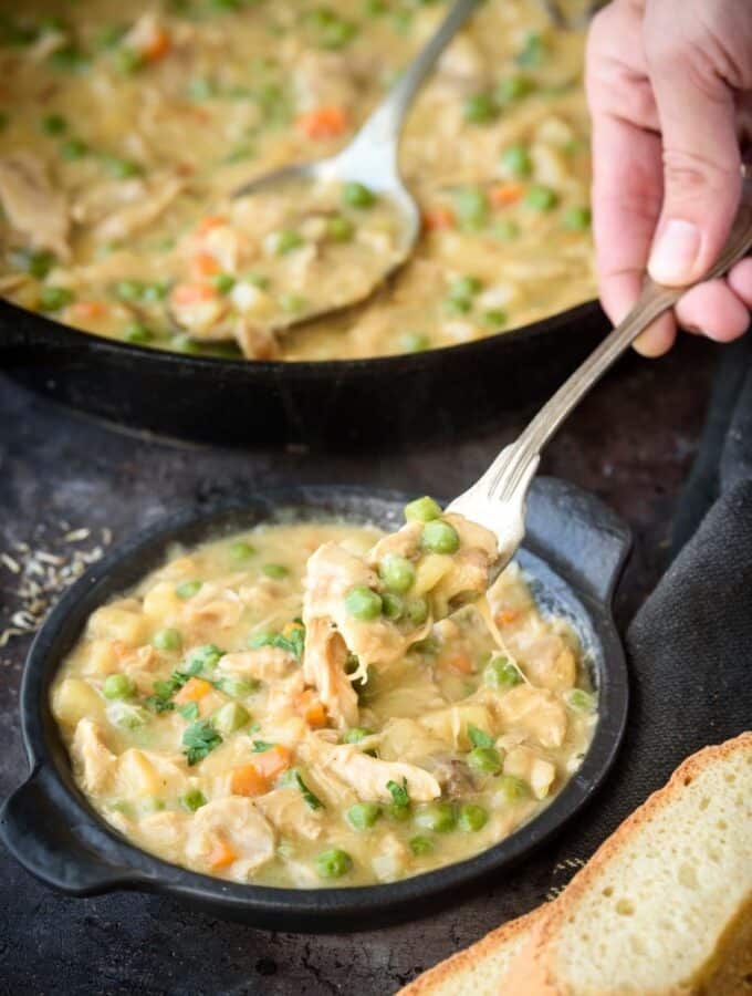 A fork lifting a portion of crustless chicken pot pie out of a small serving pot.