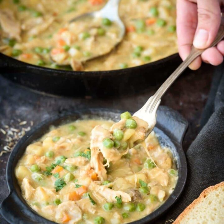 A fork lifting a portion of crustless chicken pot pie out of a small serving pot.