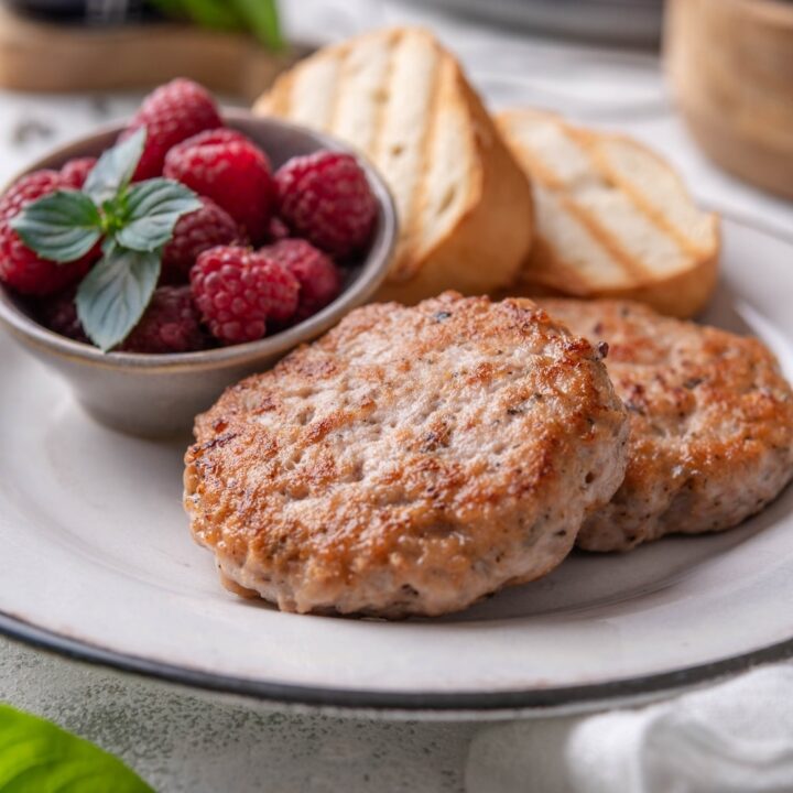 A closer look at a plate of turkey sausages paired with toasted baguette slices and raspberries.