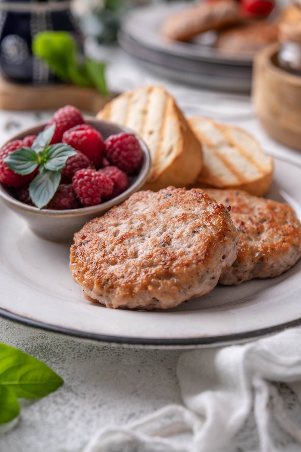 A closer look at a plate of turkey sausages paired with toasted baguette slices and raspberries.