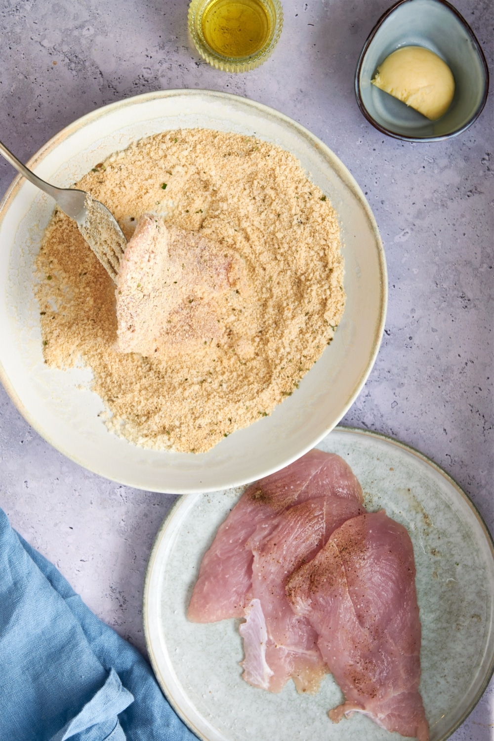 Coating turkey cutlets in a shallow bowl of seasoned parmesan and breadcrumbs.