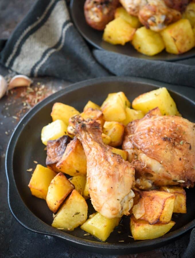 Two pieces of chicken on top of potatoes on a plate.