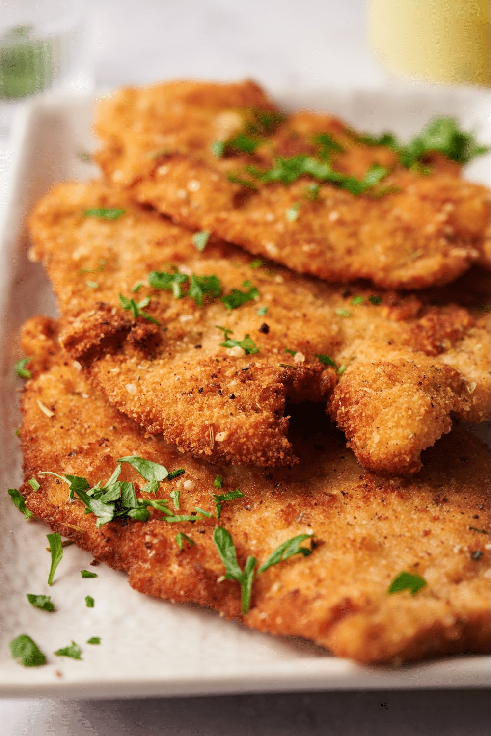 Three pieces of chicken cutlets overlapping one another in a dish.