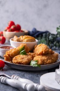 A few chicken tenders overlapping one another on a grey plate.