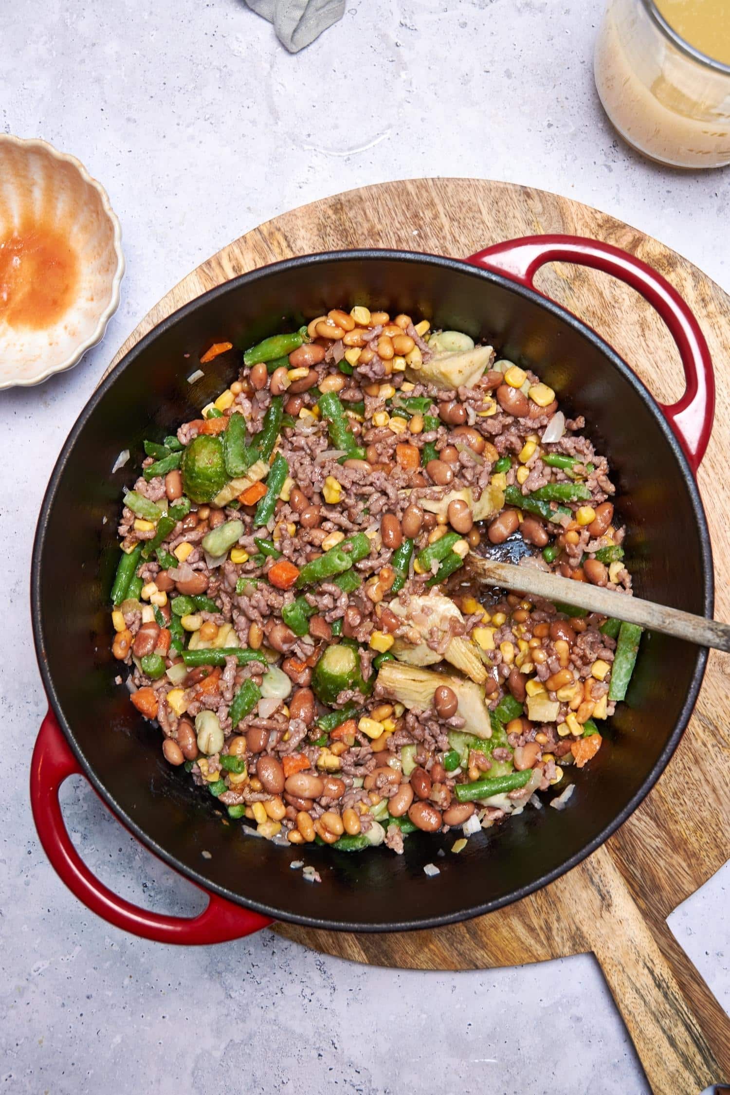 Ground beef and chopped vegetables in a pot with a wooden spoon.