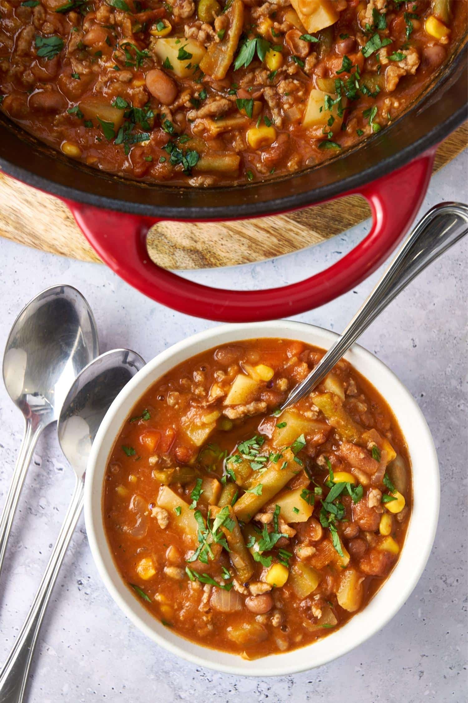 A bowl of cowboy soup with a spoon next to a large pot of cowboy soup.