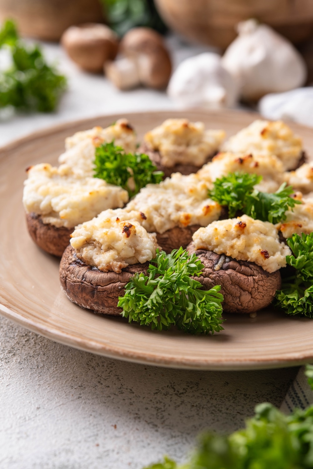 Part of a plate that has stuffed mushrooms filled with cream cheese on it.