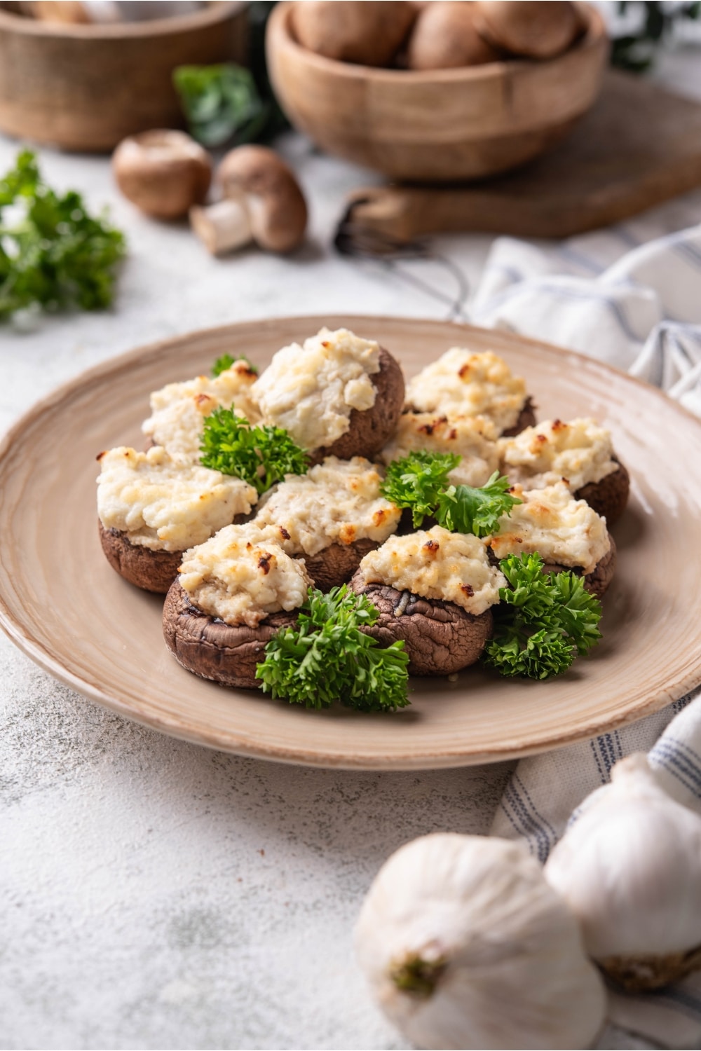 A bunch of mushrooms that are filled with cream cheese together on a plate on top of a white counter.